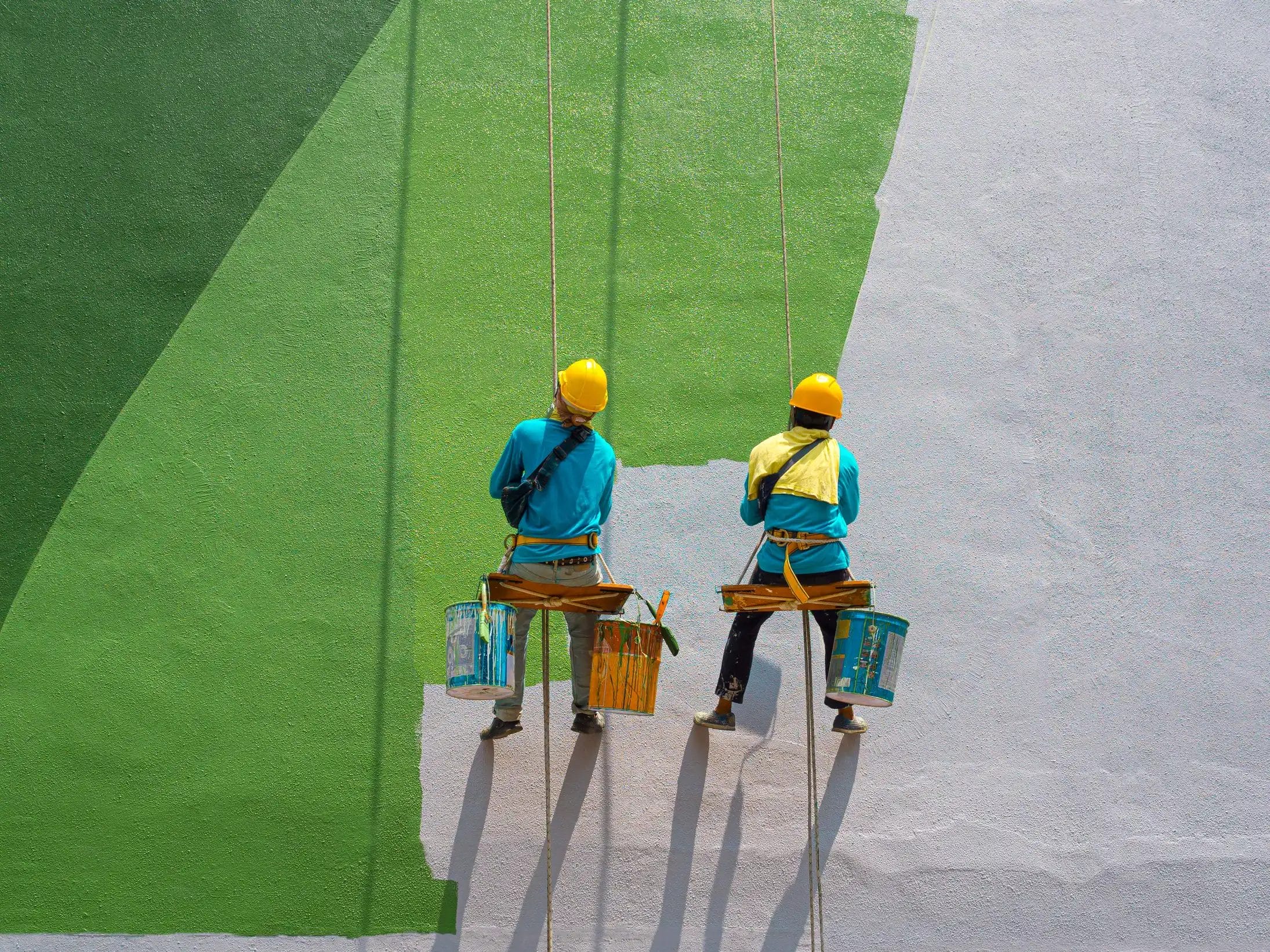 Dos trabajadores realizando trabajos de pintura en altura